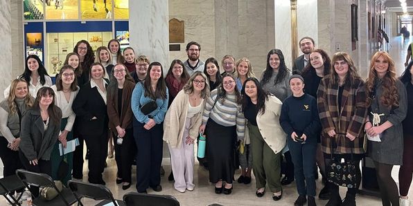Large group of social work students pose for a photo in the capitol building of Charleston, WV